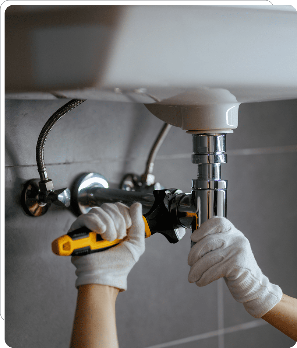 Person tightening pipe connections under sink